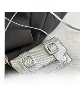 Détail du mini sac bandoulière argenté avec texture en fibre de carbone et boucles carrées