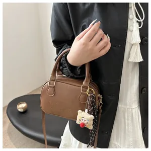 Détail d'un sac bowling en cuir marron avec lettres embossées et charm en peluche