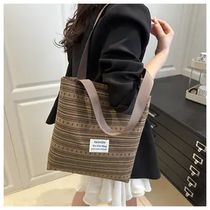 Détail d'un grand sac cabas tissé à rayures marron avec de larges bandoulières
