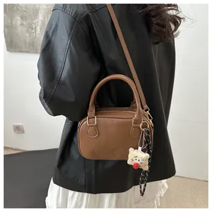 Détail du sac bowling en cuir marron avec gravure GIOH'20 et breloque en peluche