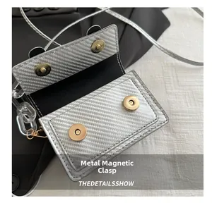 Détail du sac bandoulière argenté avec double fermoir magnétique et texture carbone