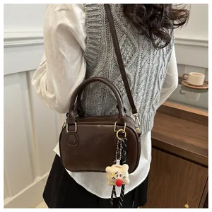 Détail du sac boston en cuir marron café avec gaufrage CIOH'20 et breloque peluche