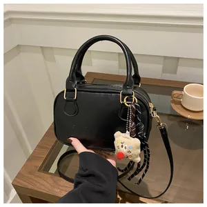 Gros plan sur le sac bowling en cuir noir avec détails dorés et pendentif ours en peluche
