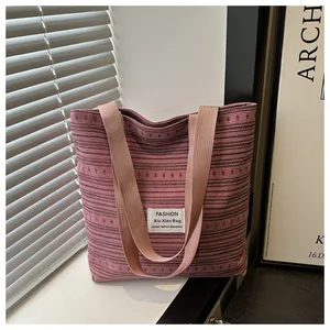 Gros plan du sac cabas en toile rayée rose avec poignées tissées et patch décoratif
