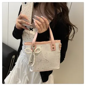 Détail du sac seau à imprimé papillon avec nœud en perles et bordure en cuir rose