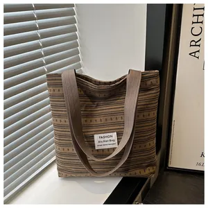 Gros plan d'un sac cabas en toile à rayures marron et noir avec des poignées tissées