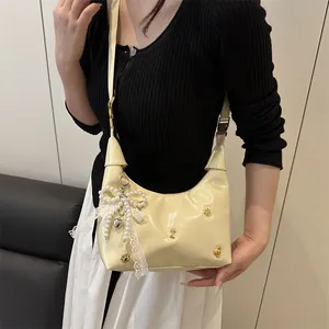 Sac hobo crème avec nœud en dentelle et perles porté par un mannequin au style épuré