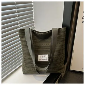 Détail du sac cabas en toile vert olive avec texture horizontale et étiquette en tissu
