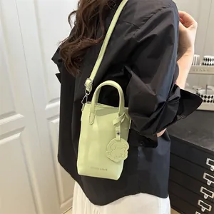 Minimalist light green vertical bucket bag with shoulder strap and puppy charm accessory