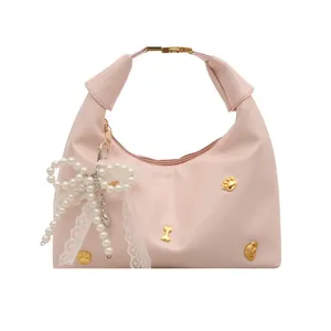 Sac dumpling rose minimaliste avec nœud en perles et breloques dorées