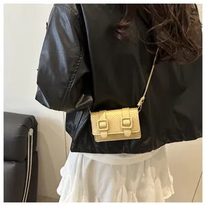 Détail d'un mini sac bandoulière doré à texture tressée sur une veste en cuir noir