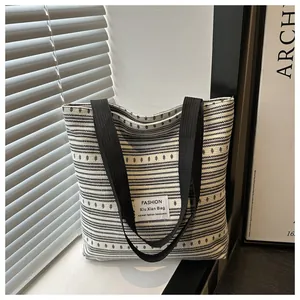 Détail d'un grand cabas en toile à rayures noires et blanches avec un écusson en tissu
