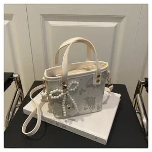 Détail du sac seau imprimé papillon avec breloque nœud en perles et pendentif cœur