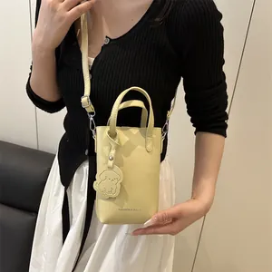 Vertical minimalist yellow bucket shoulder bag with adjustable strap and dog charm