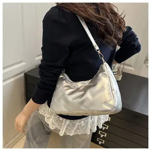 Details der silbernen Metallic-Achseltasche mit Steppmuster und Goldbuckle am Modell
