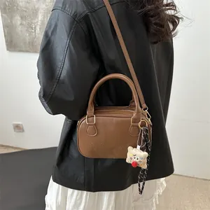 Sac bowling rétro marron avec logo embossé, charm peluche et détail foulard