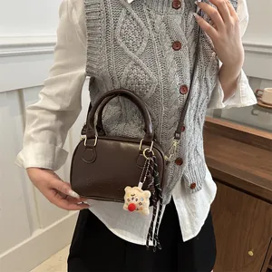 Sac bowling vintage marron foncé avec poignées et bandoulière porté par un mannequin