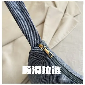 Detail of premium golden metal zipper on textured blue denim shoulder bag surface