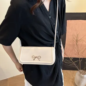 Sac bandoulière carré blanc crème élégant avec fermoir nœud doré sur modèle