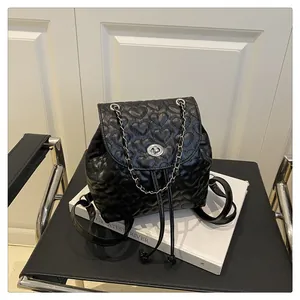 Detail eines schwarzen Rucksacks mit Herzsteppung und silberner Kette auf einem Stuhl