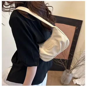 Close-up of cream textured fabric underarm bag with pleated design on a model