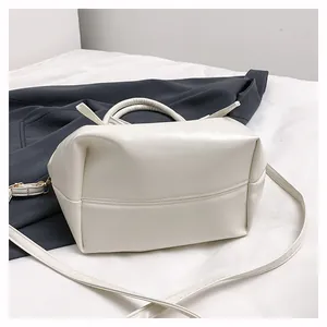 Detail of cream-colored bucket bag in textured PU leather with bow-tie accent