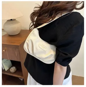 Close-up of cream textured hobo shoulder bag with fashion logo and wide strap