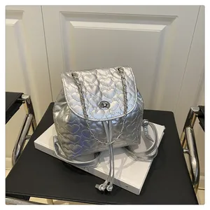 Detail eines silbernen Rucksacks mit Herzsteppung, Metalldrehverschluss und Kettenriemen
