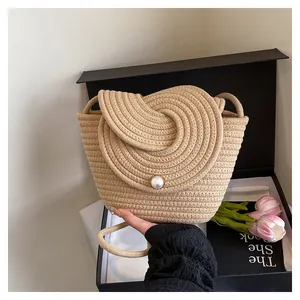 Détail d'un sac seau en paille avec fermoir perle géante et texture tressée