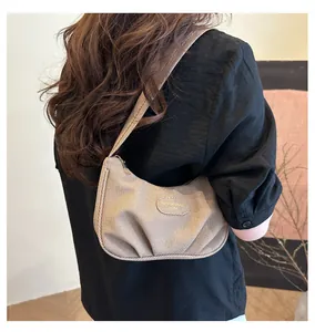 Detail showing beige pleated shoulder bag with textured fabric and gold logo plate