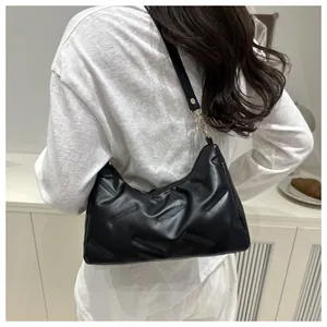 Detail der schwarzen Stepptasche mit goldener Hardware und geometrischer Lederstruktur