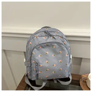 Detail view of floral print backpack with dual zippers and adjustable grey straps