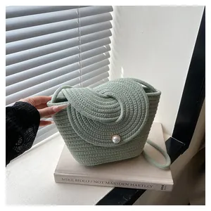 Détail d'un sac bandoulière tressé vert sauge avec fermeture à perle élégante