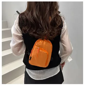 Detalle de vista trasera de un bolso bandolera de nylon naranja brillante en modelo