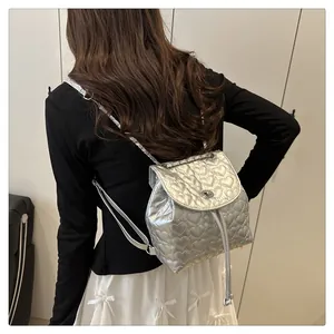 Silberner Rucksack mit Herzsteppung und Metallic-Finish, getragen von einem Modell