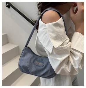 Blue striped denim underarm bag shown on shoulder with stylish pleated texture