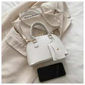 Detailed view of white semi-circular handbag with golden zippers and detachable small coin pouch