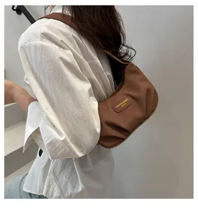 Detailed texture of brown corduroy hobo bag with pleated design and leather logo patch