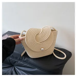 Détail du sac seau tissé beige avec boucle en perle sur surface en cuir noir chic