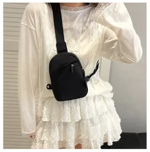 Detalle de un bolso de pecho negro compacto de nailon con doble cremallera y correa ajustable