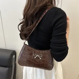 Dark brown faux crocodile leather underarm bag with silver bow buckle on model
