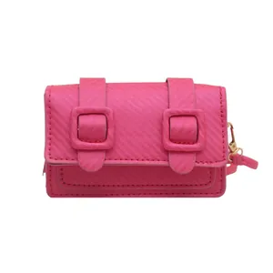 Mini sac bandoulière fuchsia texturé avec boucles décoratives sur fond blanc neutre