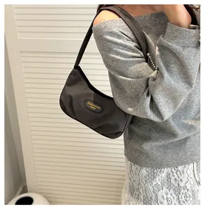 Detailed side view of grey pleated nylon shoulder bag worn by model on white background