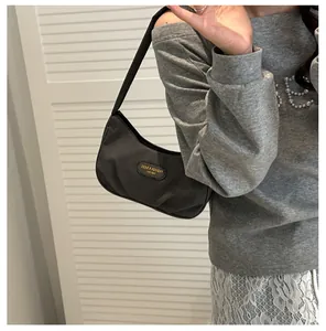 Detail of dark grey pleated hobo bag with textured fabric and metallic brand plaque