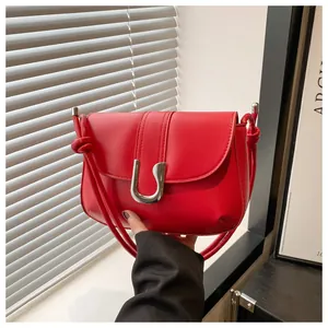 Detailed shot of red shoulder bag featuring silver U-shaped buckle and knotted strap details