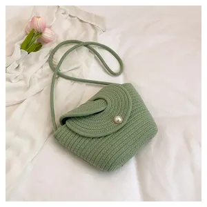 Détail du sac bandoulière tissé vert clair avec un fermoir perle blanche classique