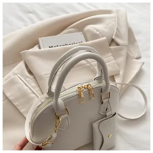 Detail of off-white shell handbag with golden hardware, detachable strap and small coin purse