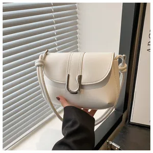 Close-up of minimalist white tote bag featuring a silver U-shaped metal buckle and knot strap