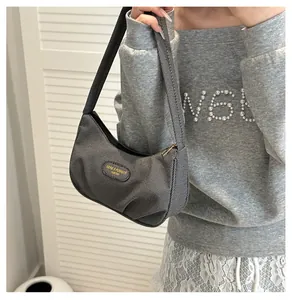 Detail of grey textured hobo bag with zip closure and fashion logo patch on the front