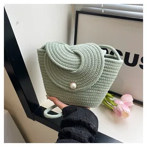 Détail du sac seau tressé vert clair avec fermoir bouton perle élégant et texture